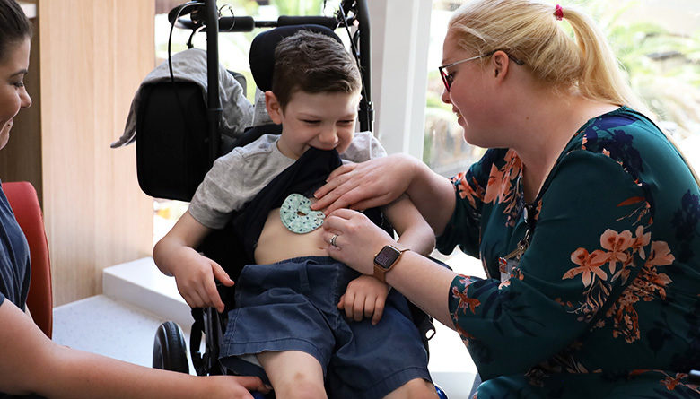 Young patient Declan in a wheelchair receiving treatment from his Nurse.