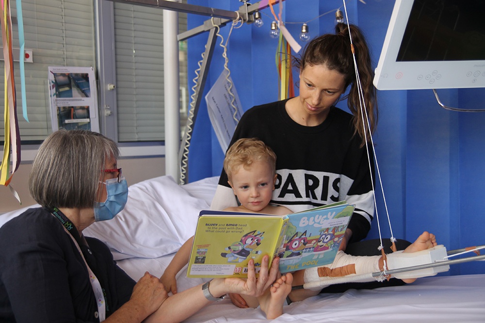 Theo and his mum being read to by Book Buddy, Chris. 
