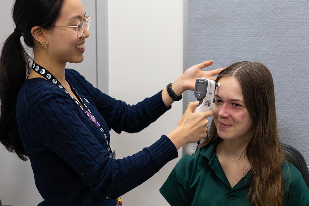 Optometrist, Claire Ong, using a tonometer on Blake. 