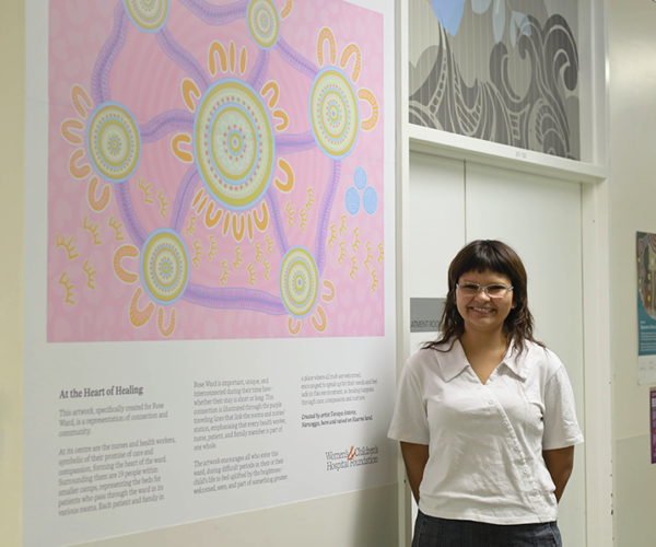 Tanaya Antony standing beside her artwork 'At the Heart of Healing' in Rose Ward at the Women's and Children's Hospital.