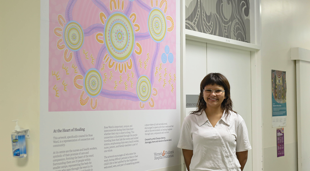 Tanaya Antony standing beside her artwork 'At the Heart of Healing' in Rose Ward at the Women's and Children's Hospital.