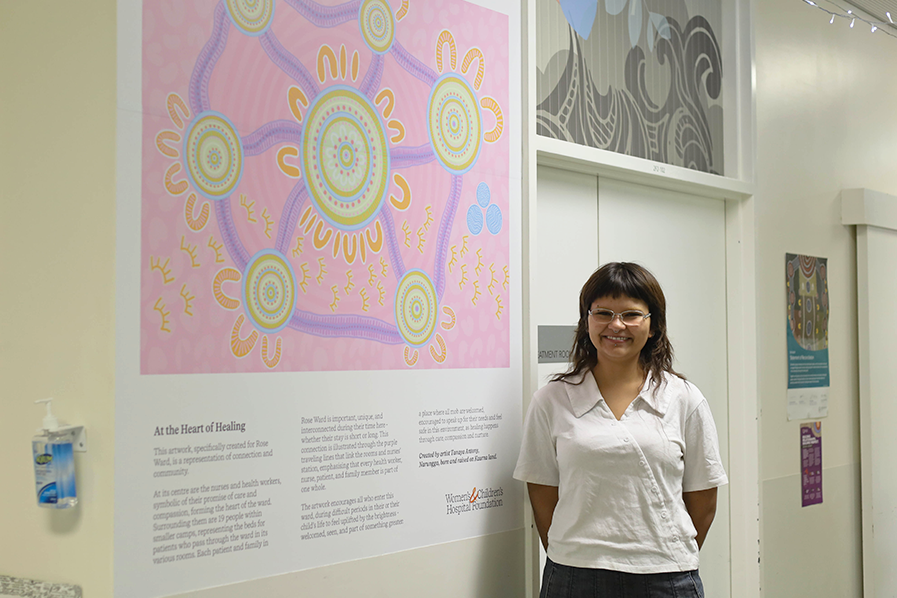 Tanaya Antony standing beside her artwork 'At the Heart of Healing' in Rose Ward at the Women's and Children's Hospital.